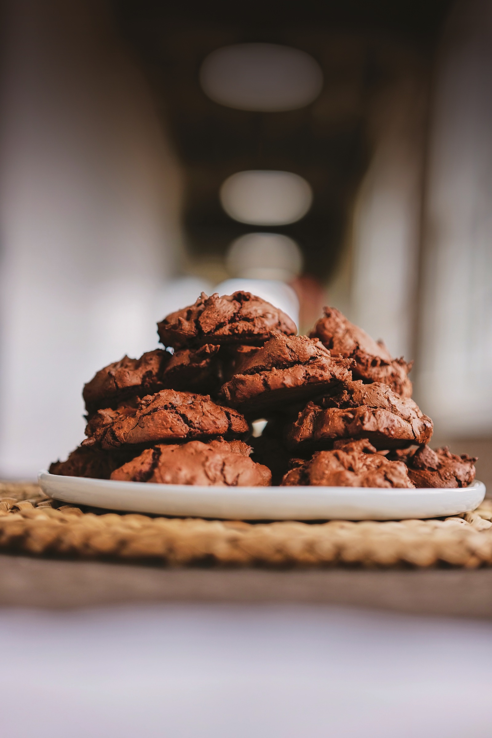 A tall pile of dark, crackled mocha cookies on a white plate.